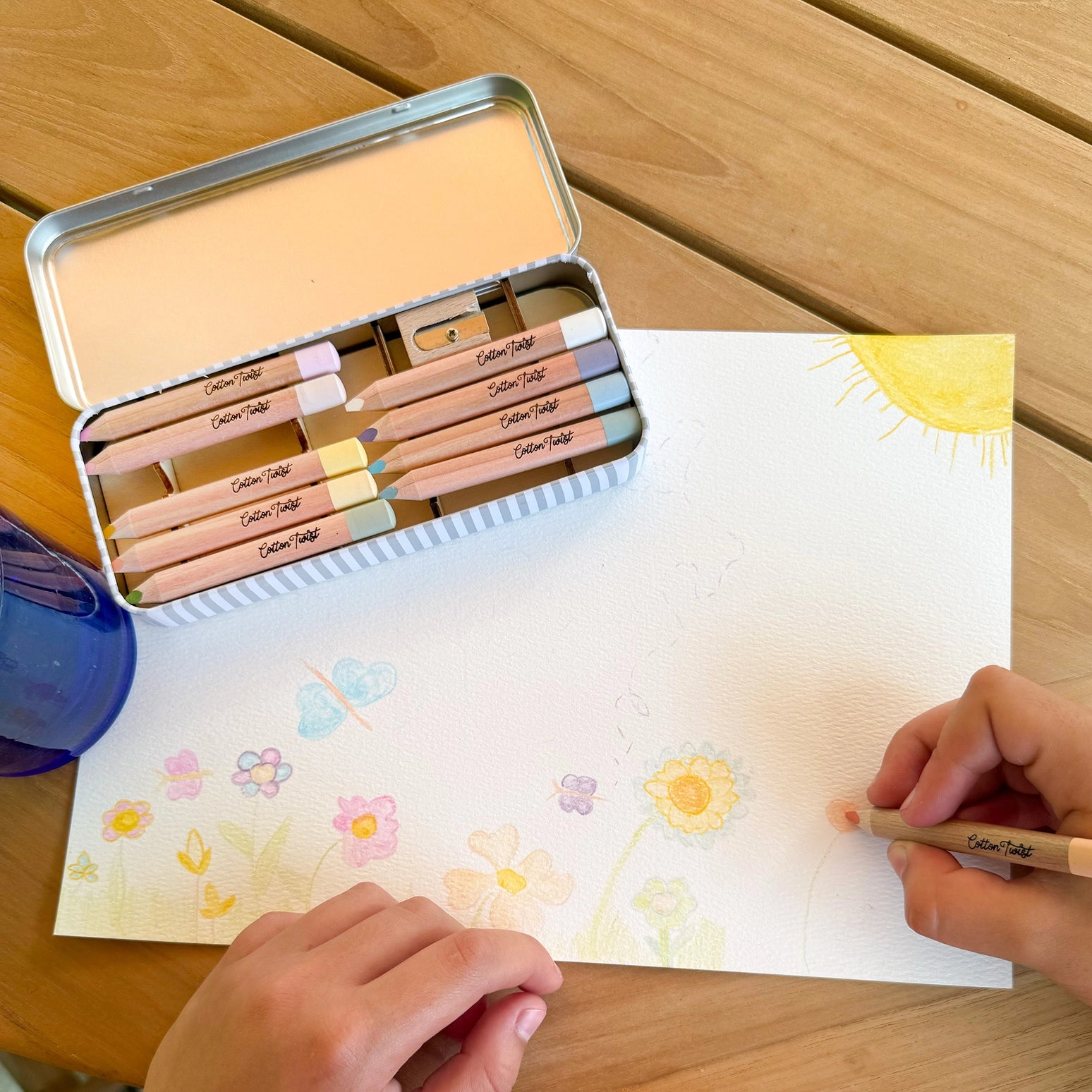 Coloring book with pencils and a tin on a wooden table
