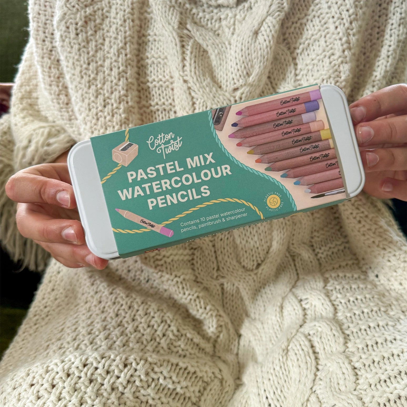 Person holding a box of Cotton Twist pastel mix watercolour pencils against a beige sweater background