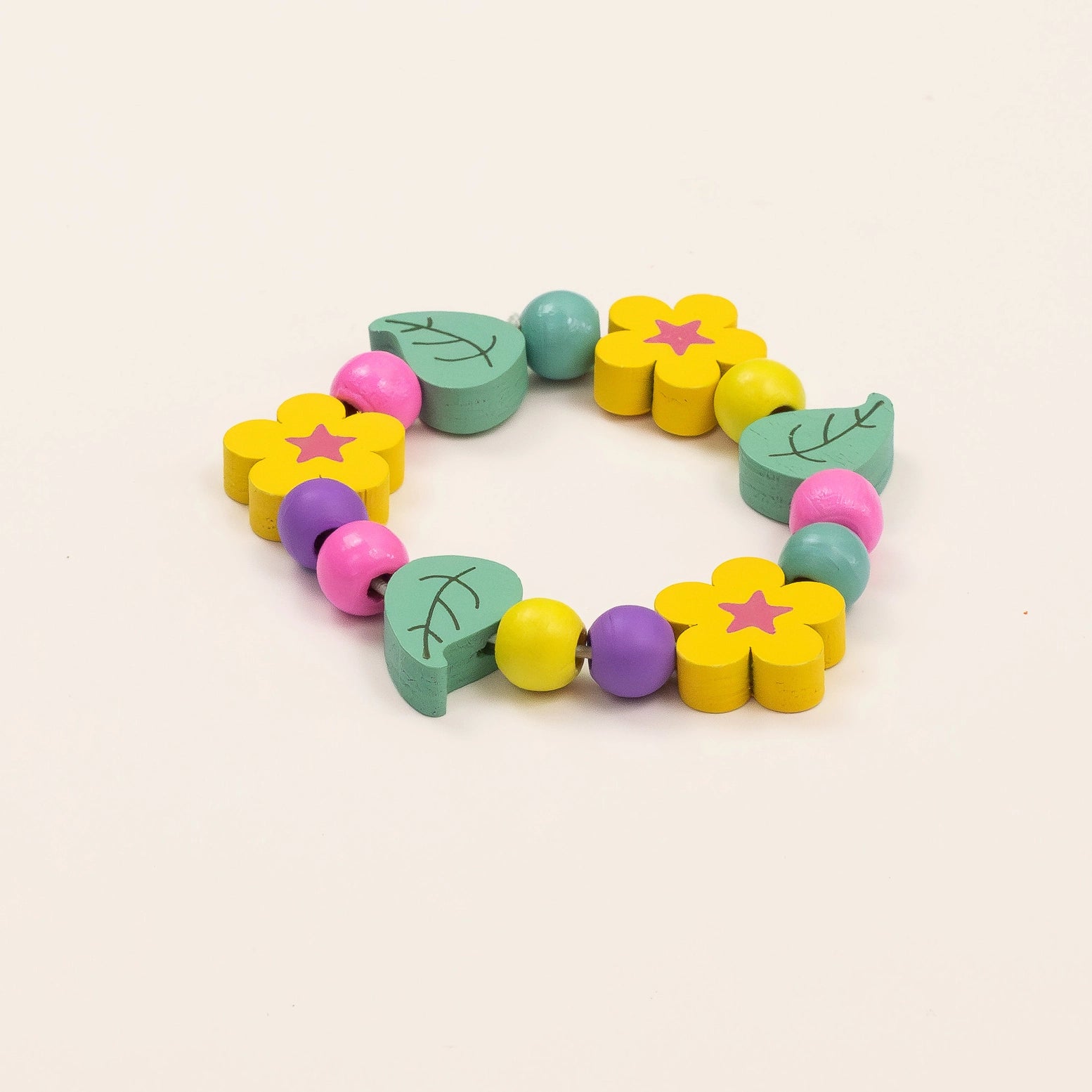 Colorful wooden teething toy with flowers and leaves on a beige background
