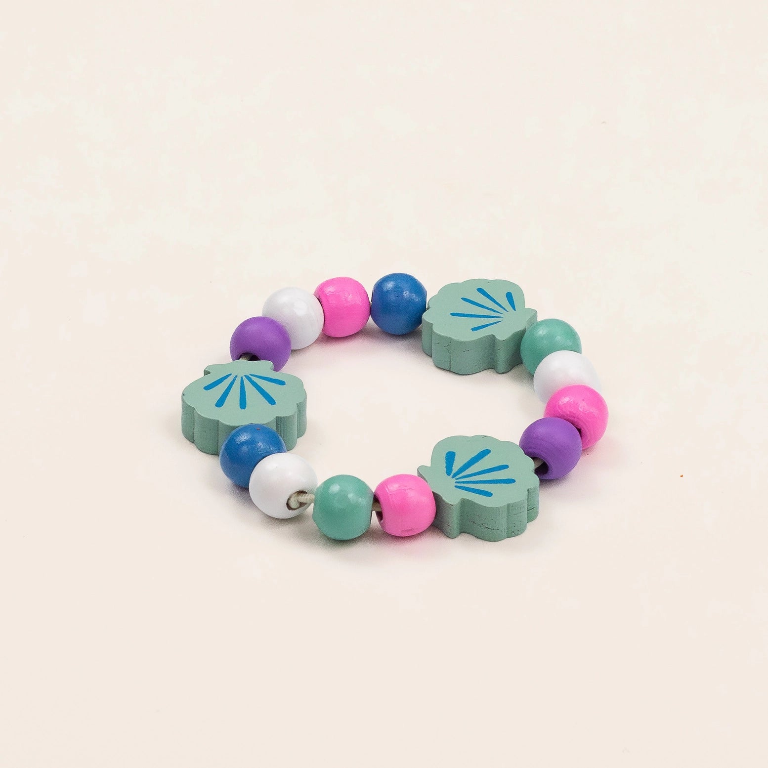 Colorful bracelet with shell-shaped beads on a beige background
