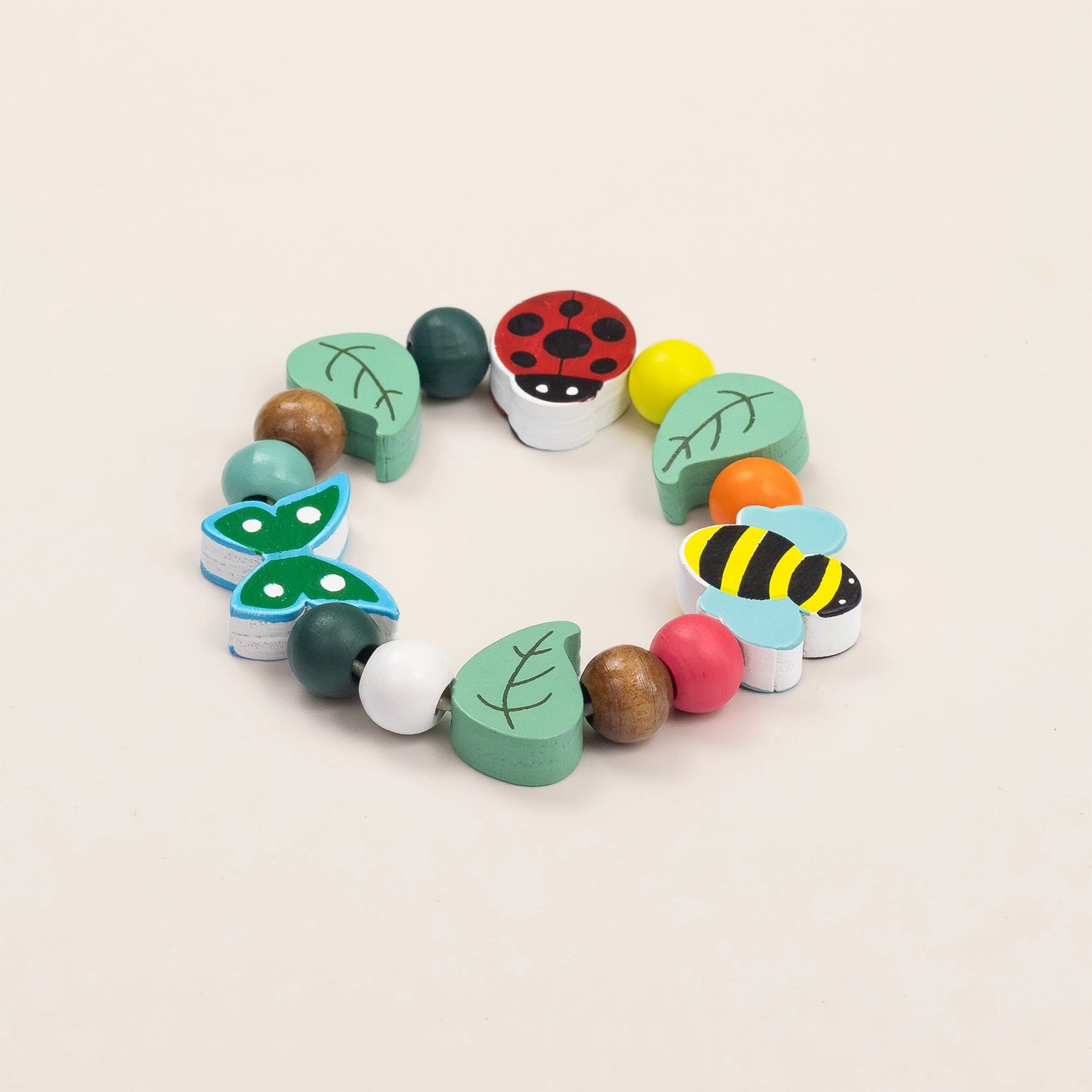 Colorful wooden teething toy with beads and shapes on a beige background