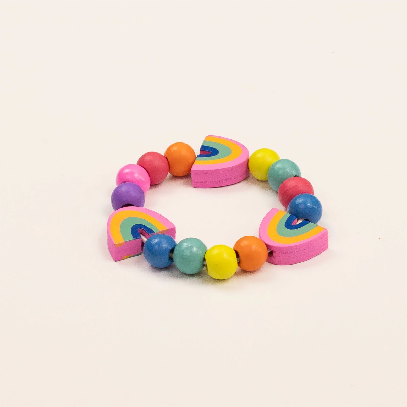 Colorful bracelet with rainbow-shaped beads on a light beige background