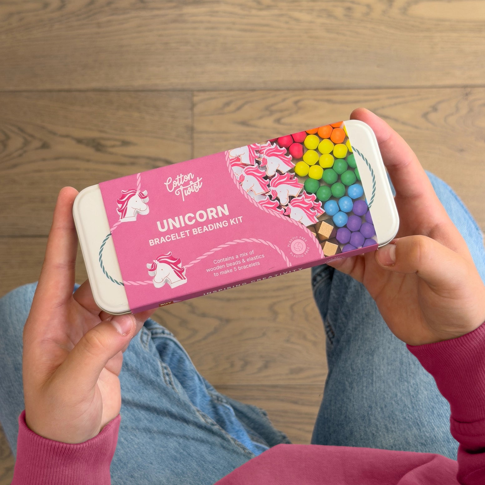 Unicorn bracelet beading kit held by a person on a wooden floor