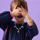 Child wearing colorful jewelry against a purple background