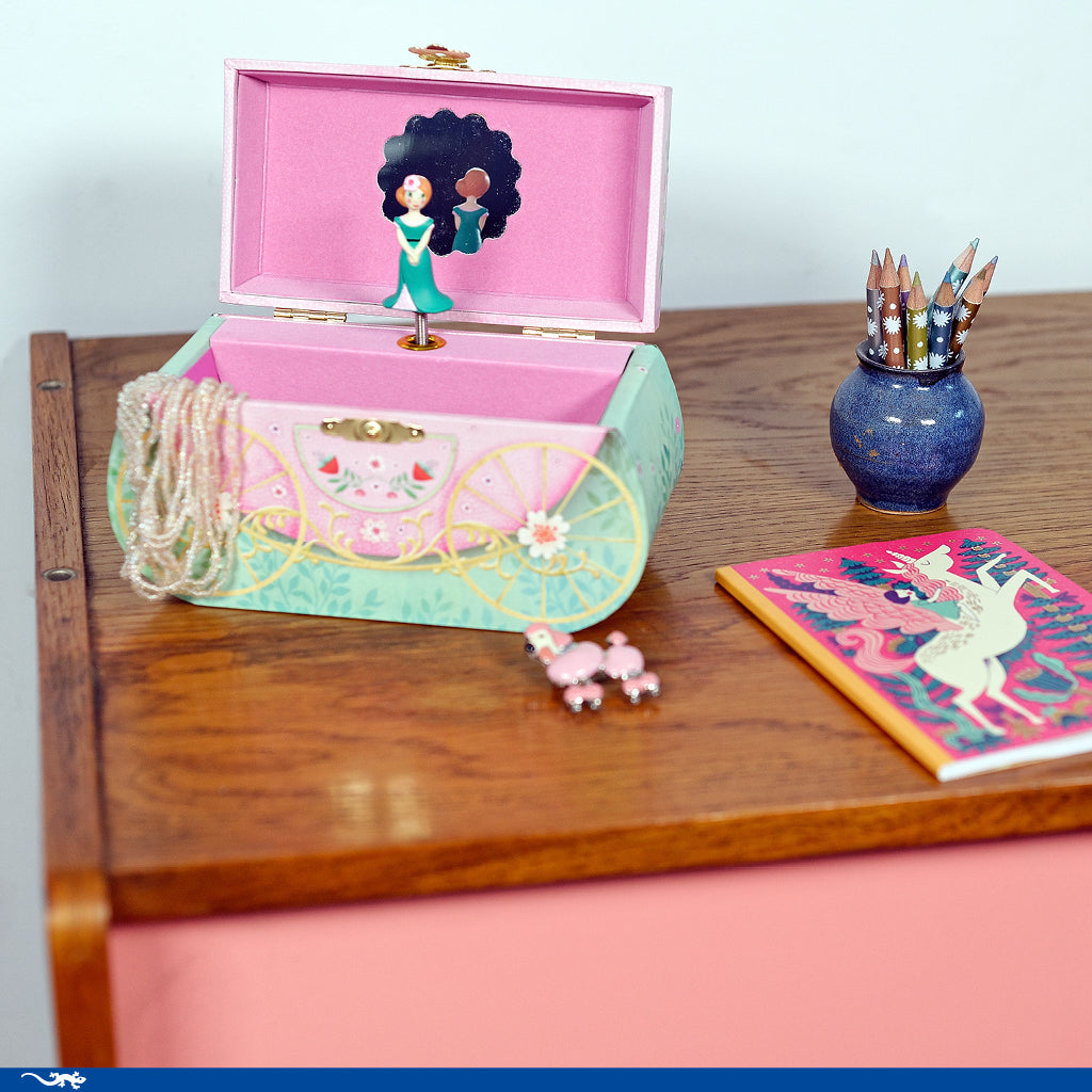 Decorative jewelry box with a character on top, surrounded by stationery items on a wooden surface.