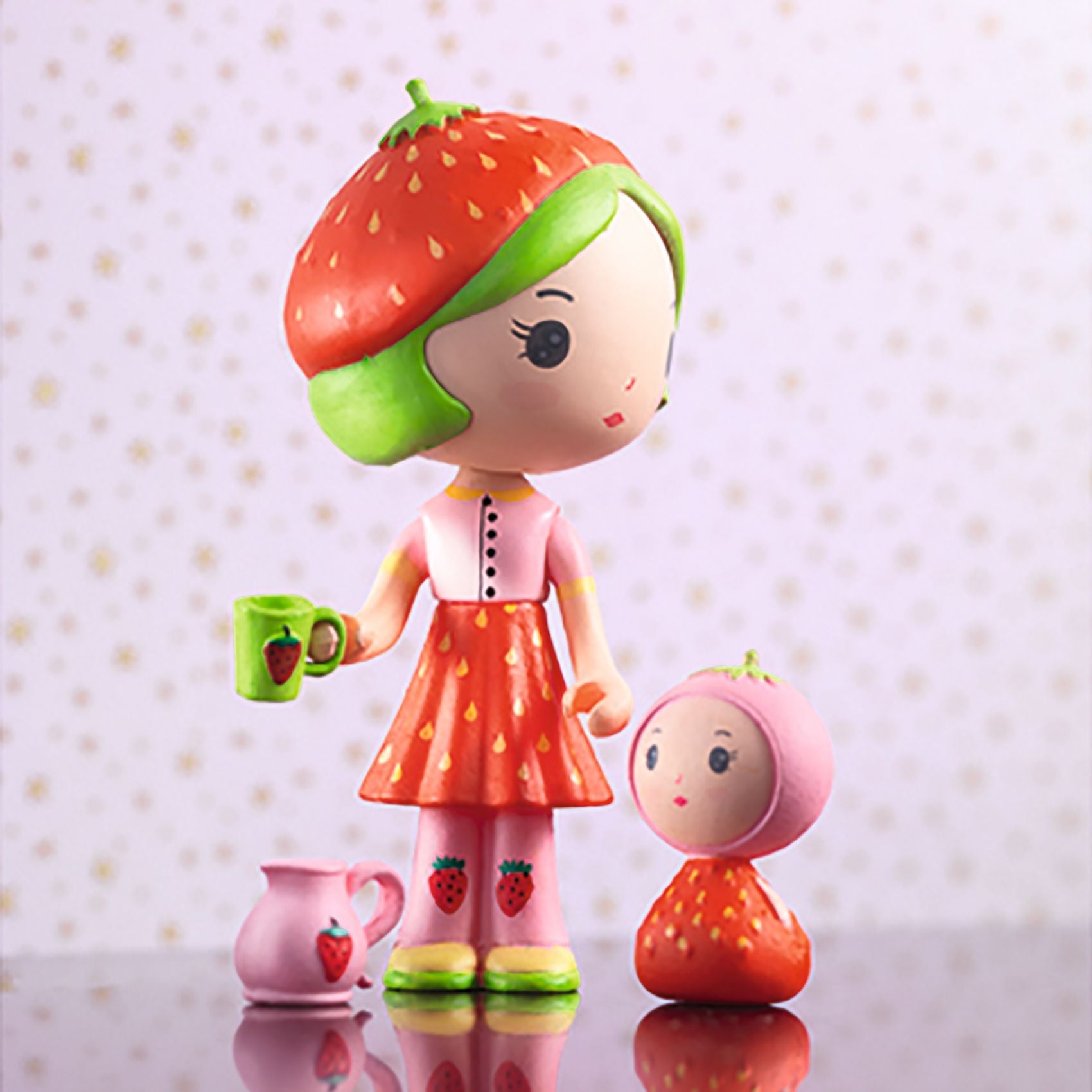 Toy figure of a girl with a strawberry hat and a smaller figure on a polka dot background