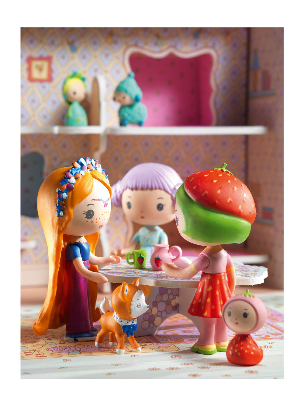Toy figures of a girl with a strawberry hat, another girl, and a dog in a colorful room.