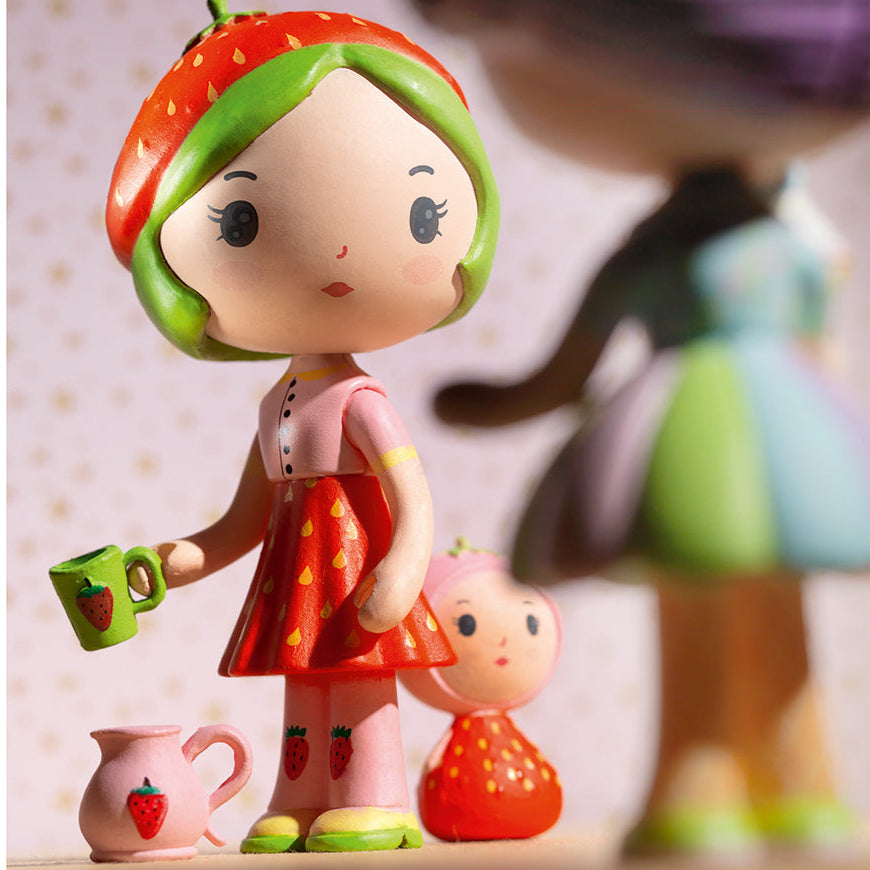 Colorful strawberry-themed figurine holding a cup with a smaller figurine beside it.