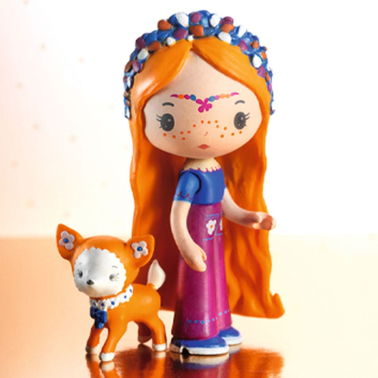 Toy figure of a girl with orange hair and a small animal on a reflective surface