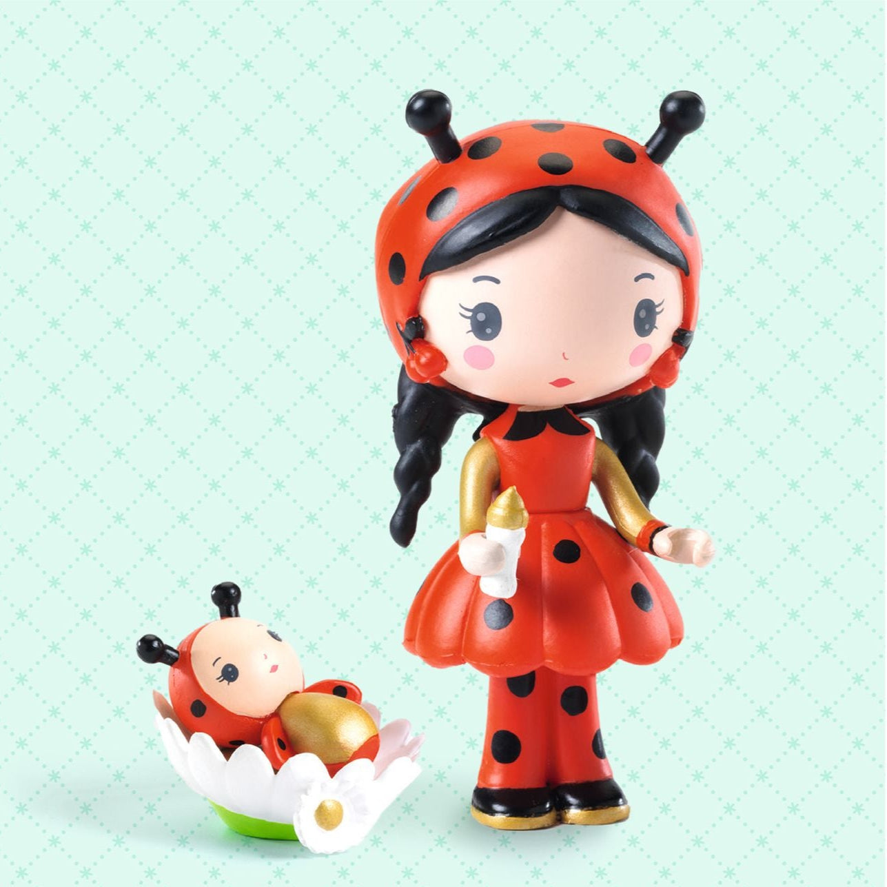 Toy figure of a ladybird girl with a baby on a light blue background, featuring the brand 'Coco & Minico' and 'tinyly'.