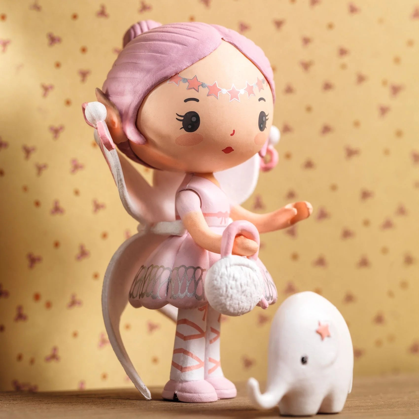 Pink fairy-like figurine with a small white creature on a patterned background