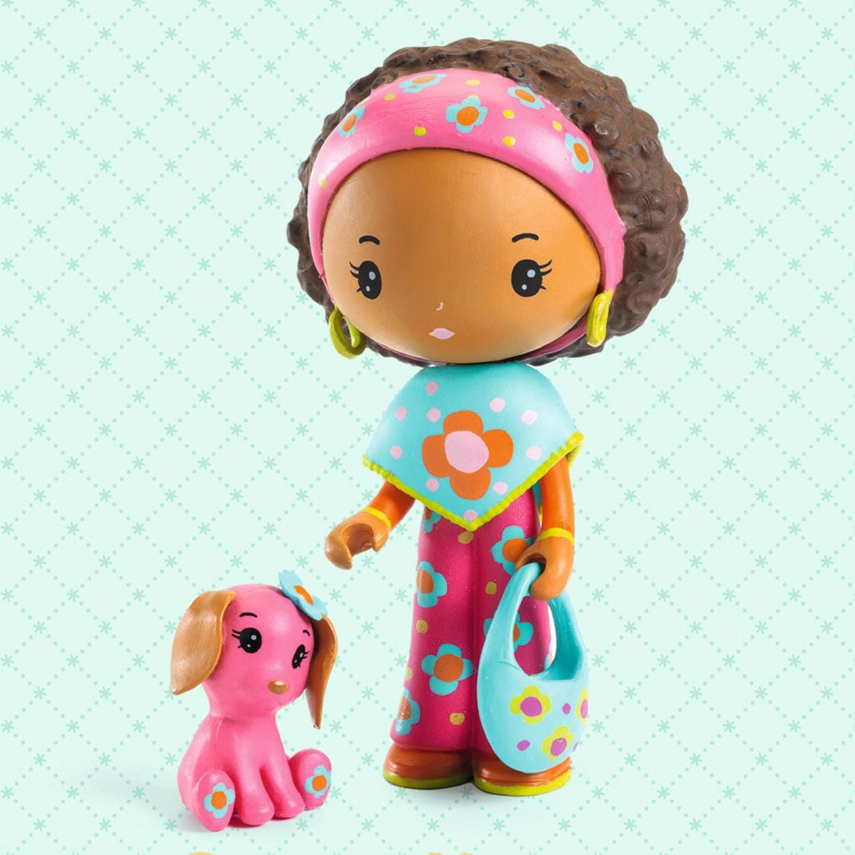 Toy figure of a girl with a pink dog on a light blue background, featuring the brand 'tinly'.