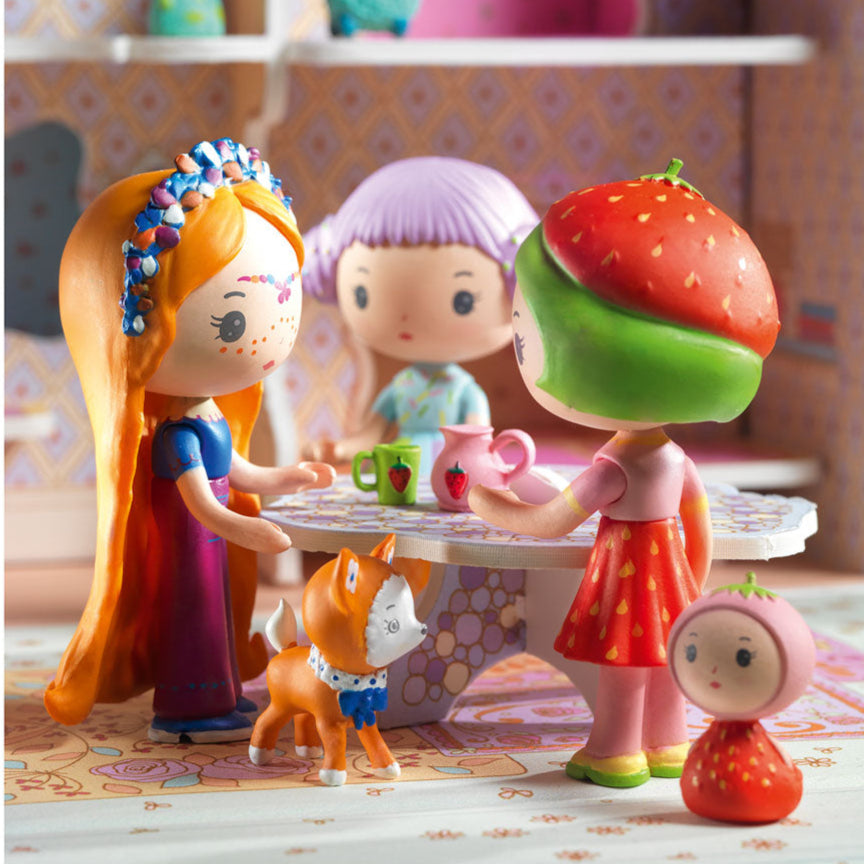 Toy figures of a girl with orange hair, a girl with purple hair, and a girl with a strawberry hat in a play setting.