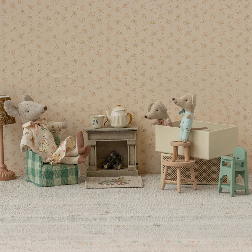 Miniature diorama with toy mice and furniture against a patterned wall.