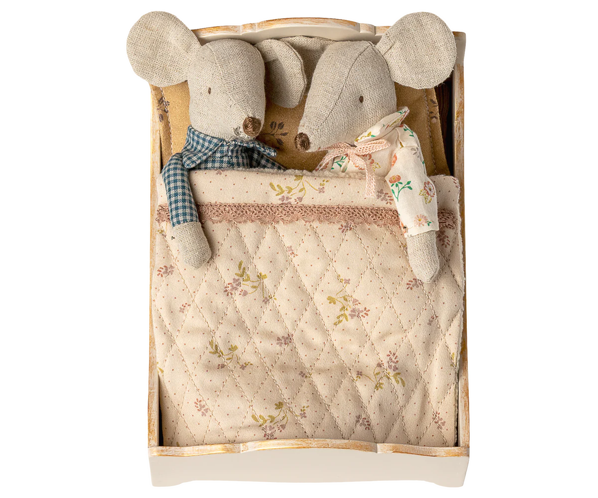 Two plush mouse toys in a wooden box with a quilted blanket