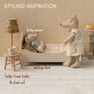 dolls house room setup with vintage bed, table, and lamp, featuring labeled items.