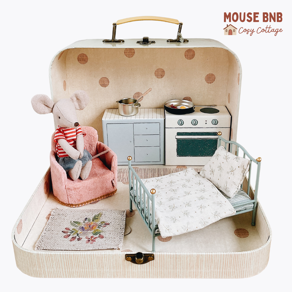 Miniature dollhouse with furniture and a toy mouse inside a suitcase, branded 'Mouse BNB'.