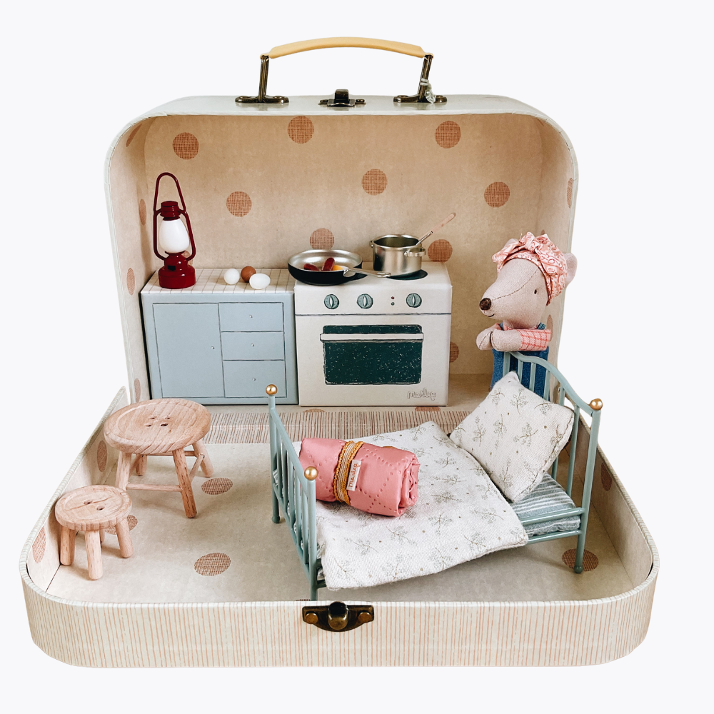 Miniature dollhouse setup inside a suitcase with furniture and accessories.