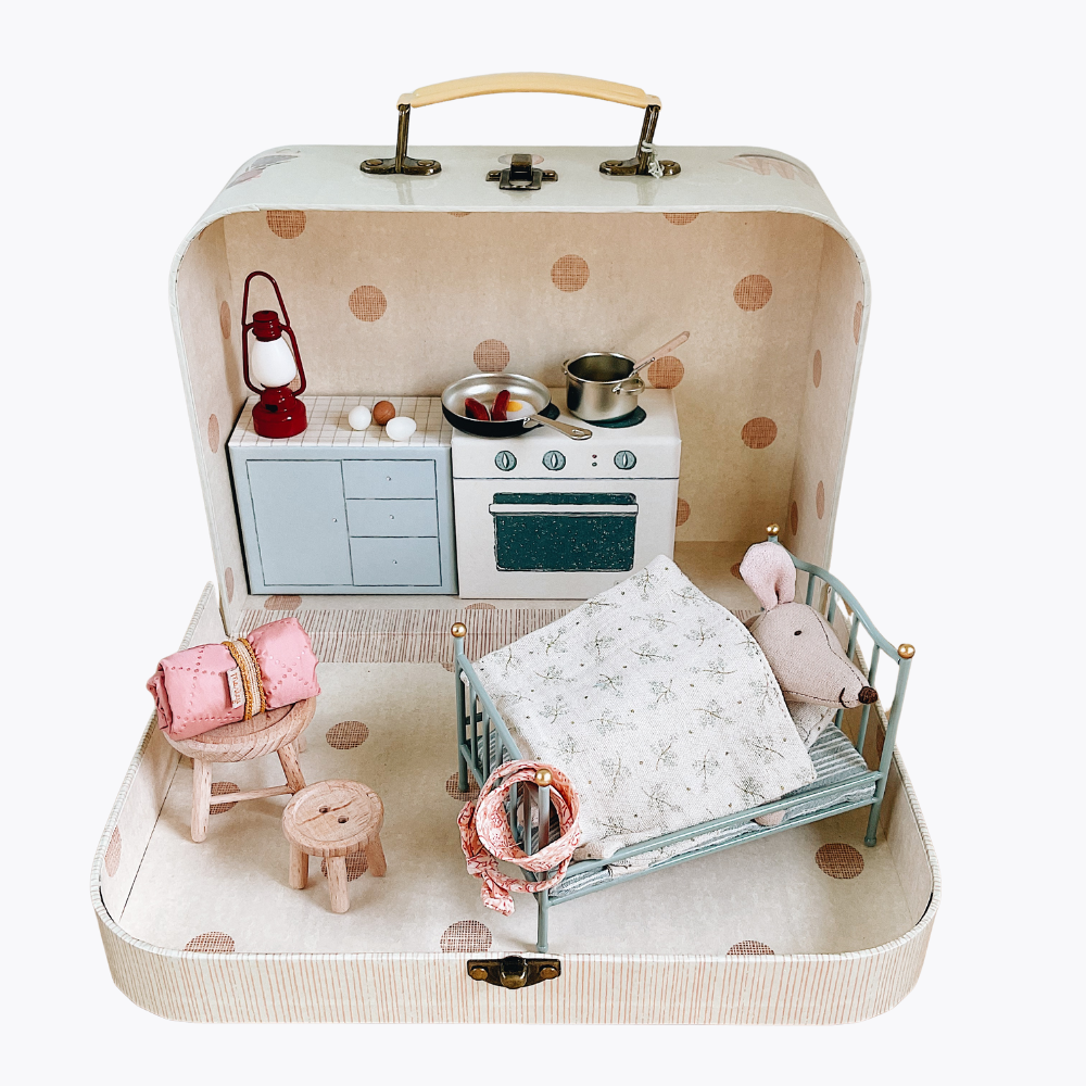 Miniature kitchen set inside a suitcase with a bed and accessories on a white background