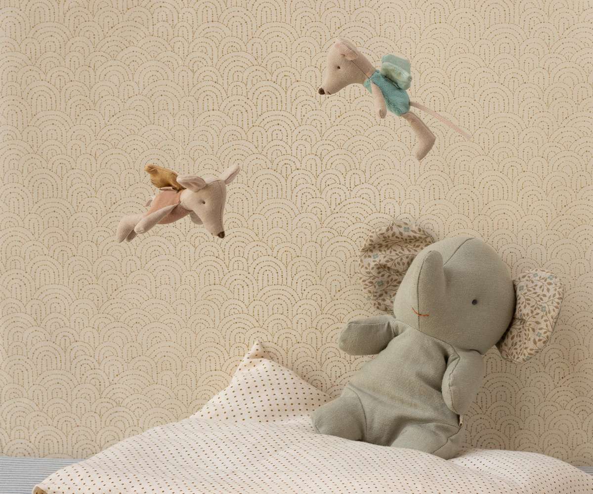 Children's room with stuffed animals on a bed against a patterned wall.