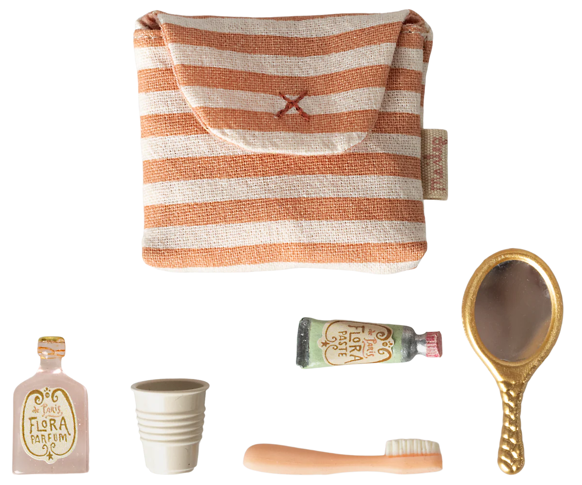 Set of travel-sized products including a striped pouch, bottle, cup, brush, and mirror on a white background.