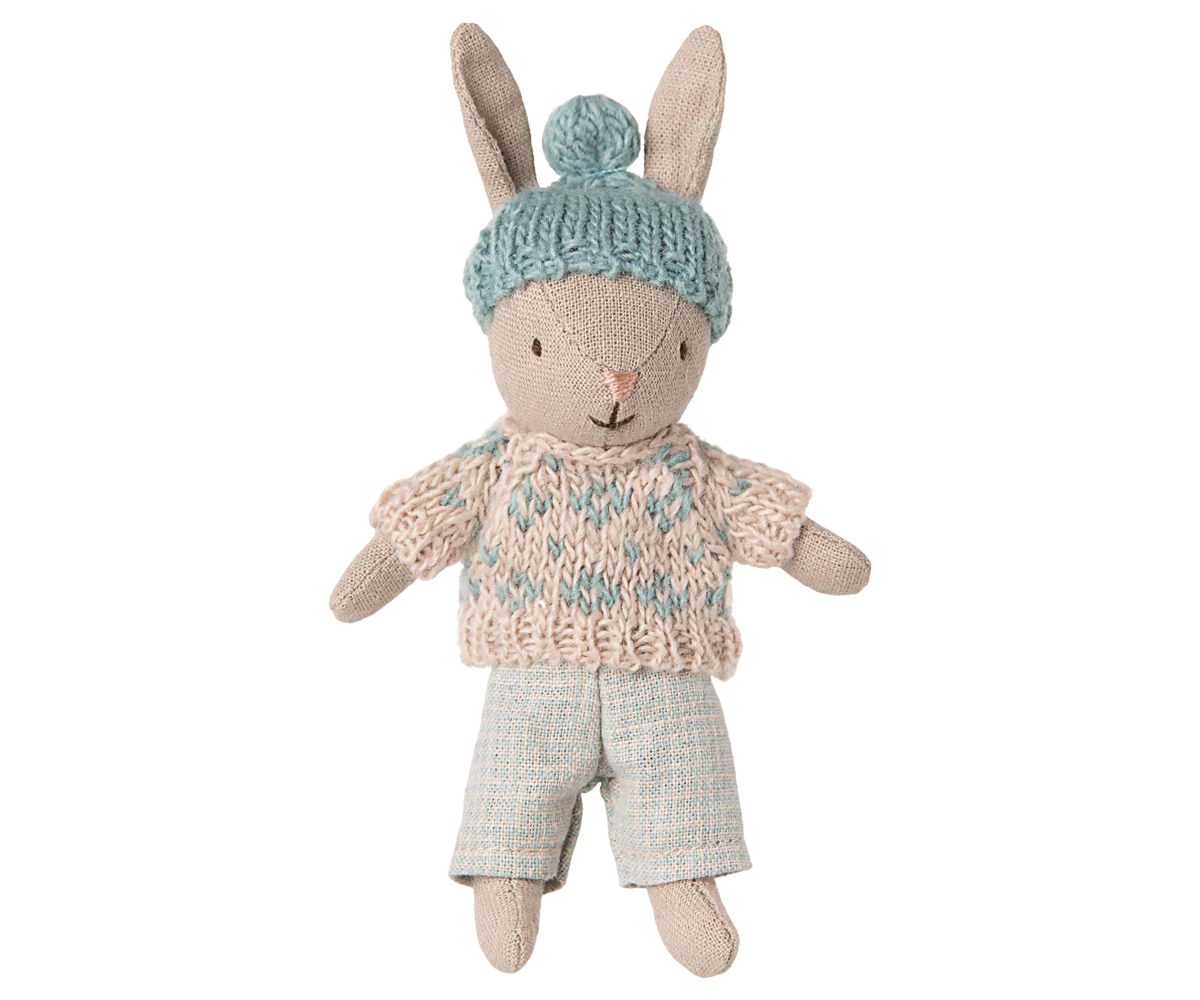 Toy rabbit wearing a knitted sweater and hat on a white background
