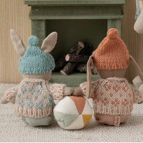 two toy rabbits sitting infront of a fire