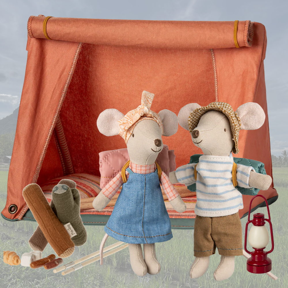 Two plush mouse dolls, a boy and a girl, standing in front of a small tent with camping accessories.