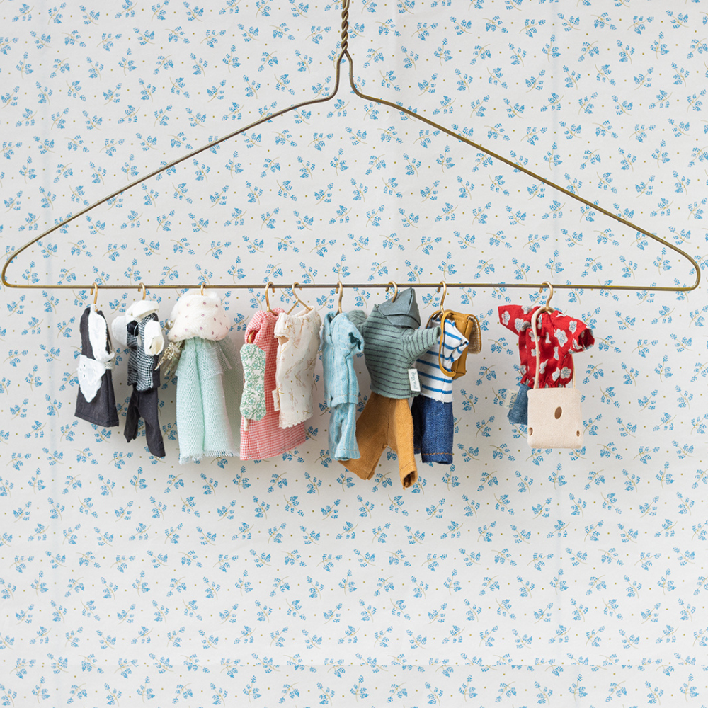 Maileg mouse clothes on a hanger against a floral wallpaper background