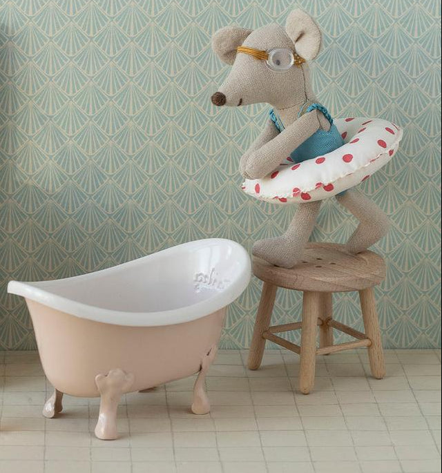 Miniature bathroom set with toilet, sink, bathtub, and decorative elements on a patterned wall background.