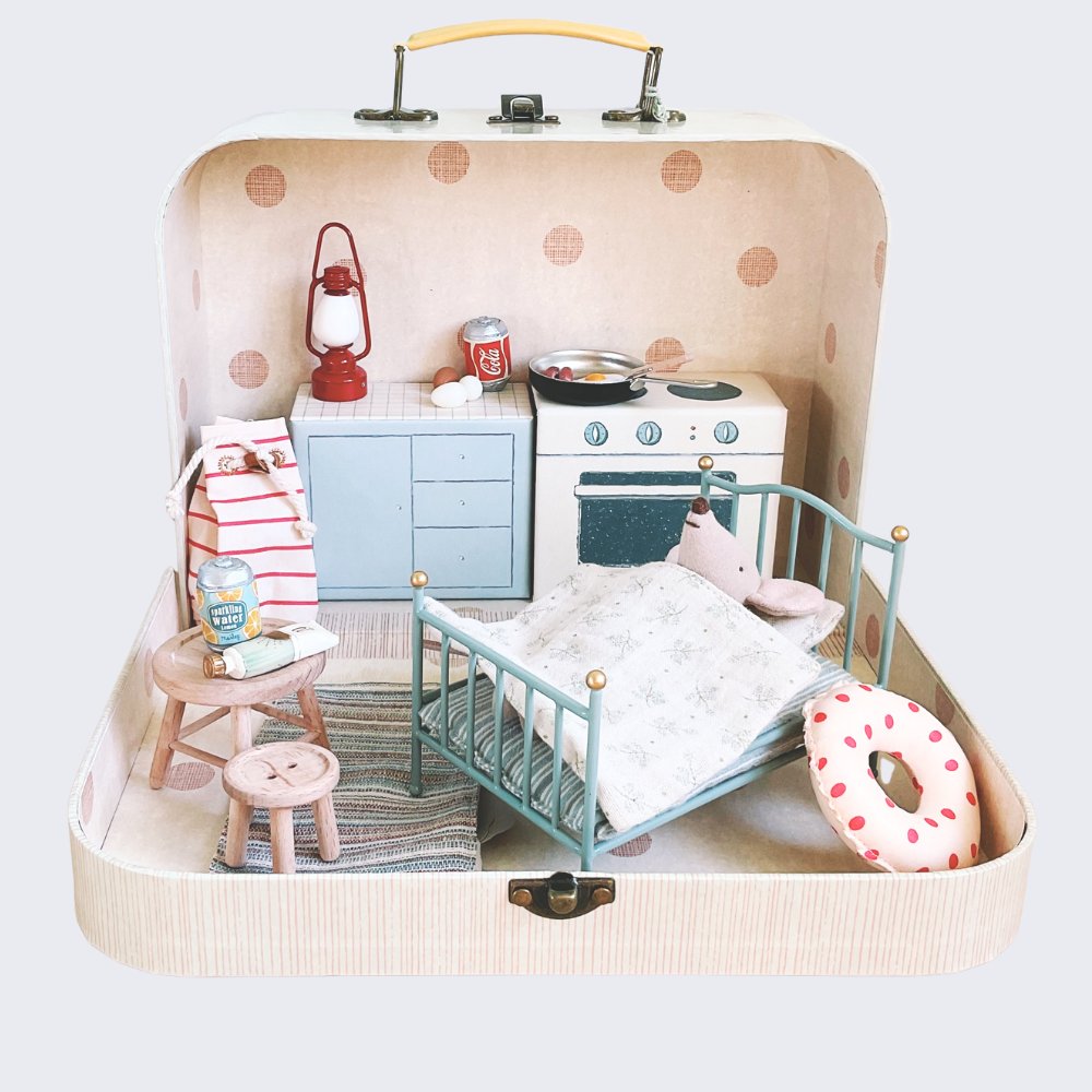 Miniature dollhouse setup inside a suitcase with furniture and accessories.