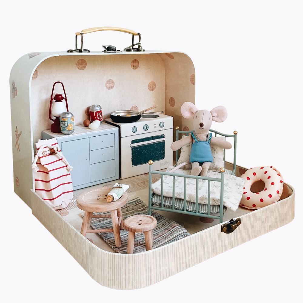 Toy suitcase with a miniature kitchen and bedroom setup on a white background