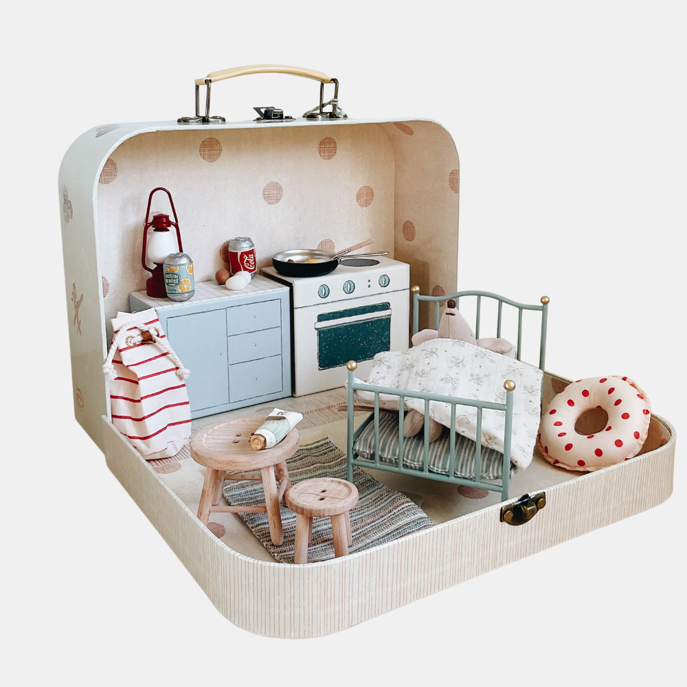 Miniature dollhouse with kitchen and bedroom setup inside a suitcase