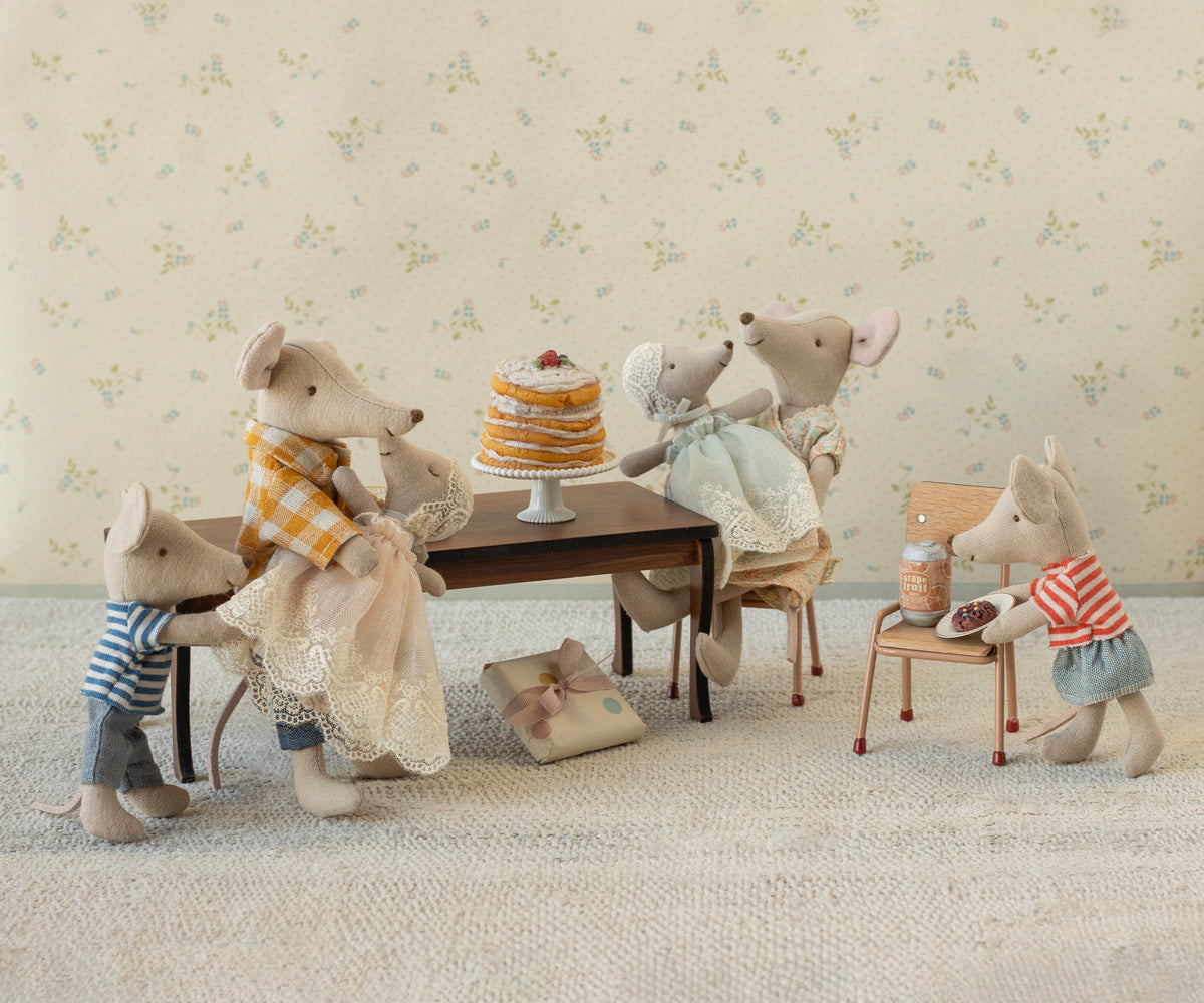 maileg mouse Stuffed animal family gathered around a small table with a cake, set against a floral wallpaper background.