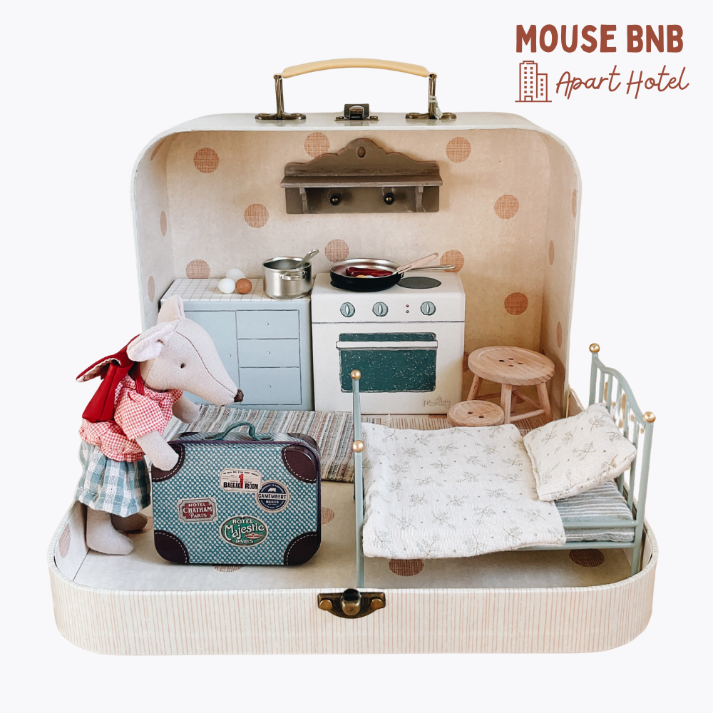 Toy miniature apartment set inside a suitcase with 'Mouse BNB Apart Hotel' branding.