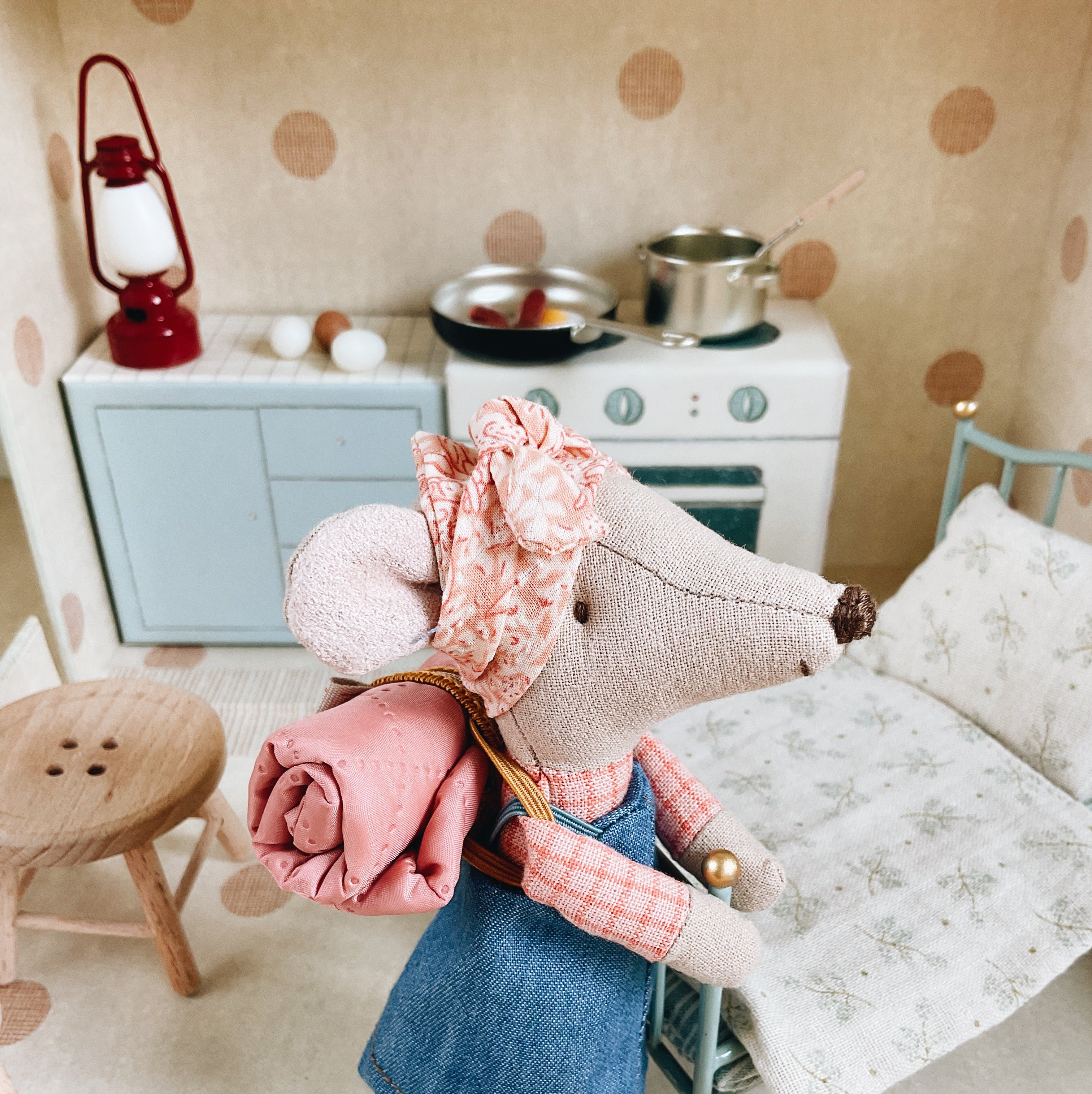 Toy mouse in a miniature kitchen setting with a polka dot wall.