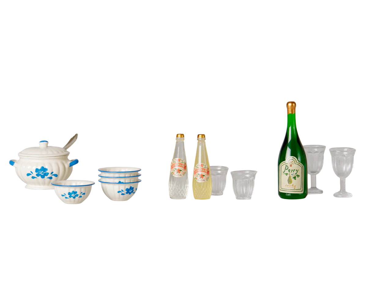 A miniature dollhouse-scale kitchen and bar set featuring a white ceramic soup pot and bowls with blue floral patterns, two clear bottles with pink floral labels, a green bottle labeled 'Berry', and several clear drinking glasses, all arranged on a plain white background.