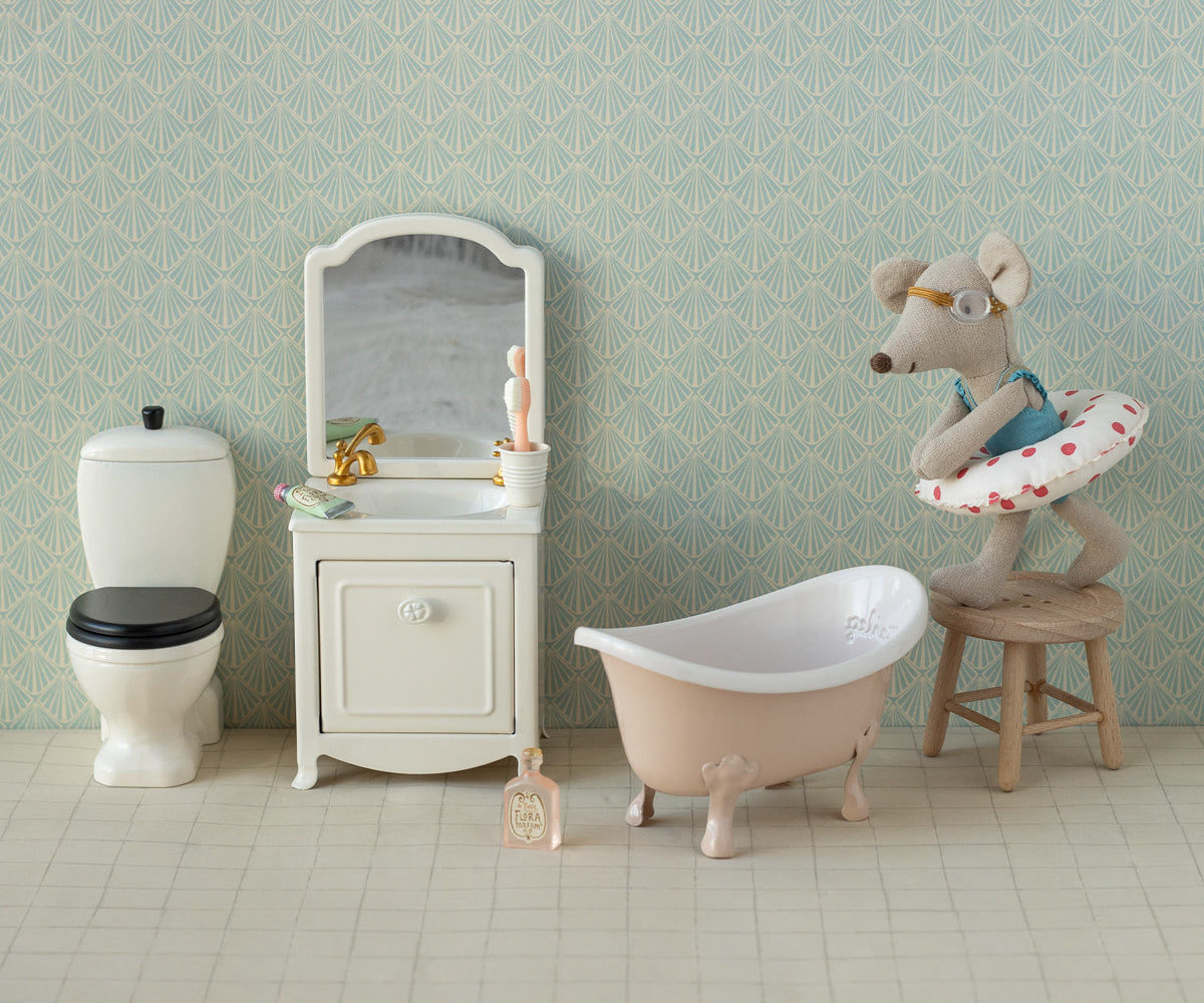 Maileg toy Miniature bathroom set with bathtub, toilet, and vanity against a patterned wall.