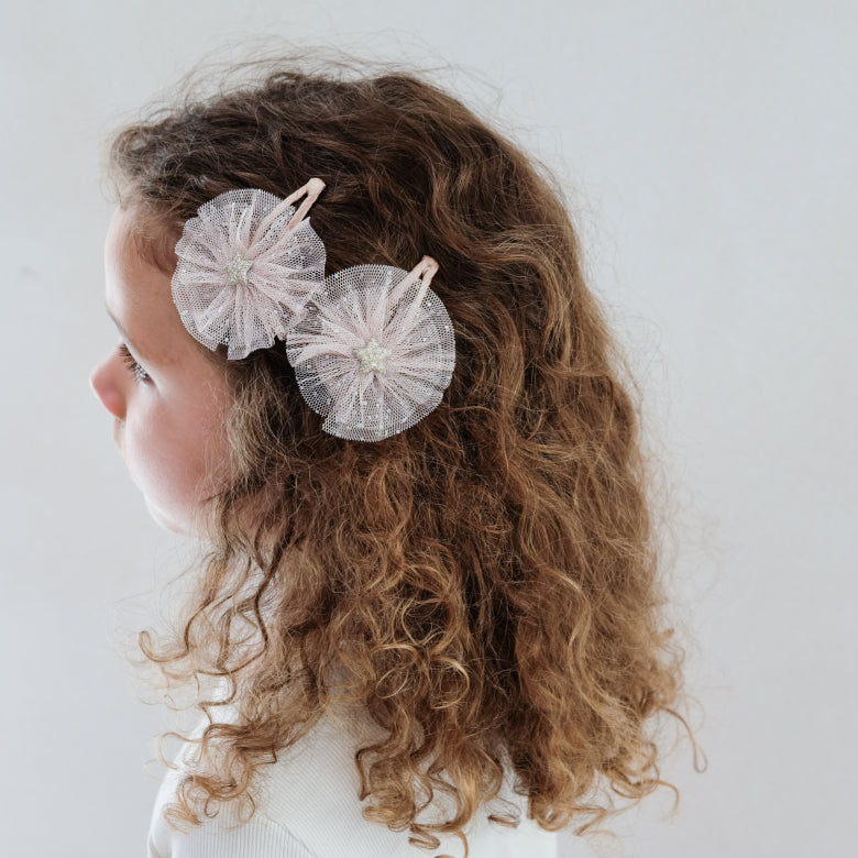 Person with curly hair wearing star clips on a plain background