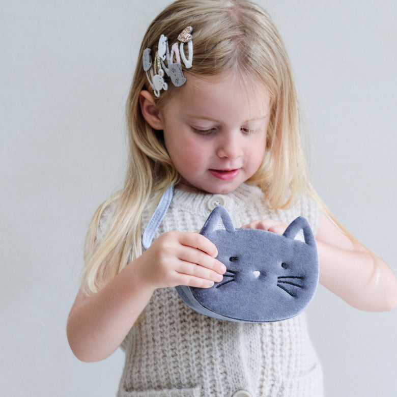 Child holding a blue cat-shaped bag against a plain background