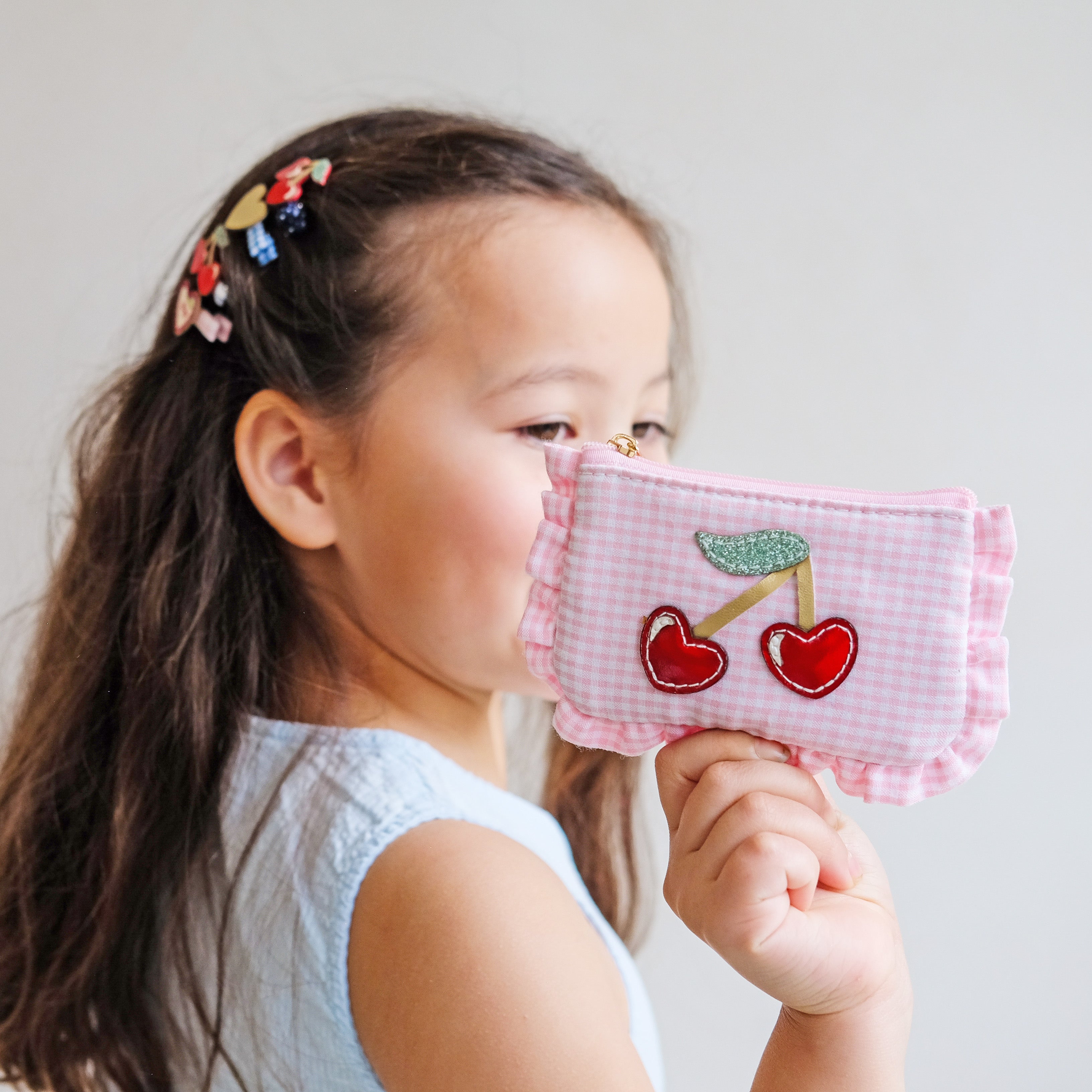 girl holding a pink gingham purse with heart shaped cherry motif
