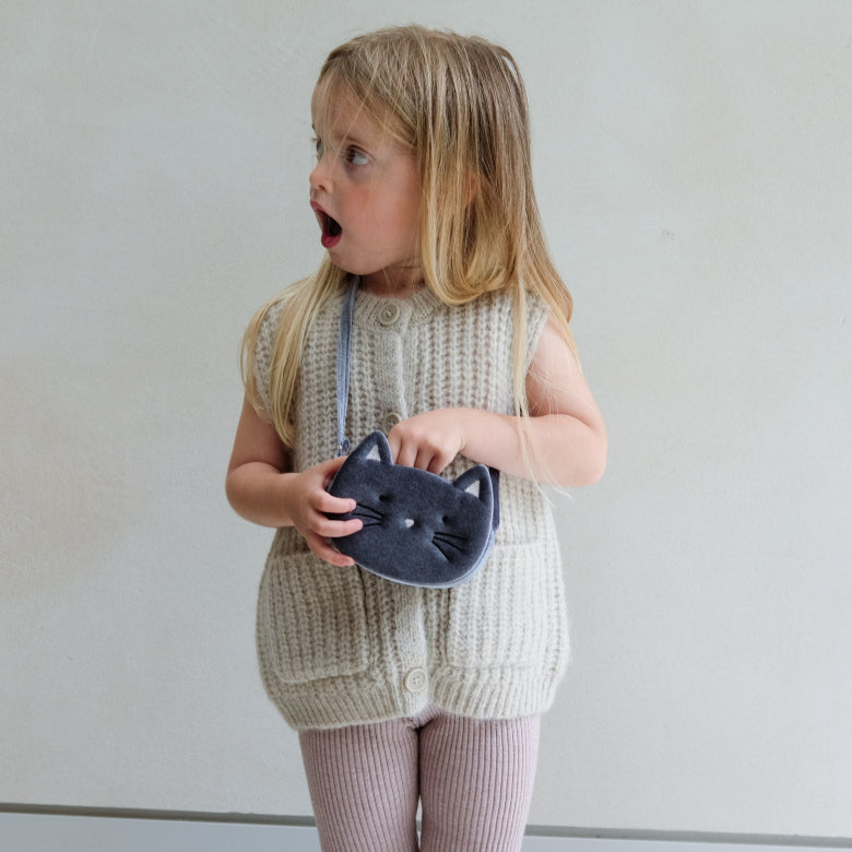 Child holding a cat-shaped pouch against a plain background