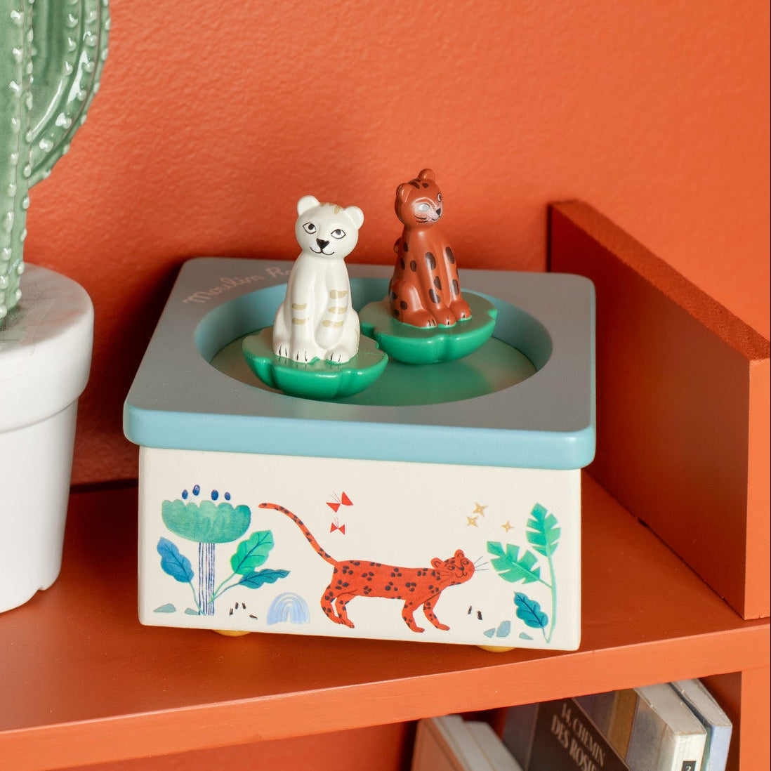 Decorative box with animal illustrations on an orange shelf against an orange wall.