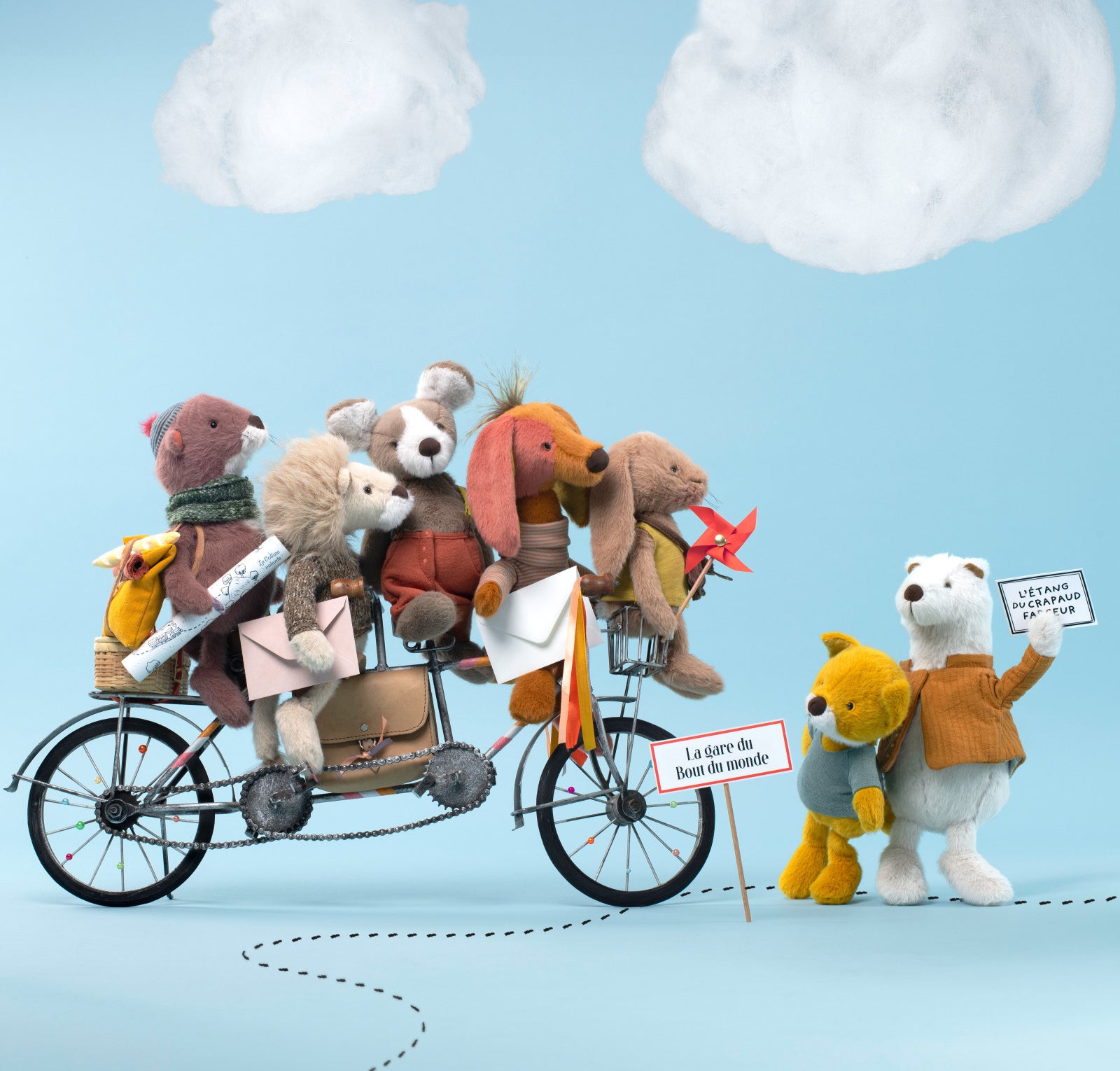 Moulin roty bande a jojo Toy bears on a bicycle with a blue sky background