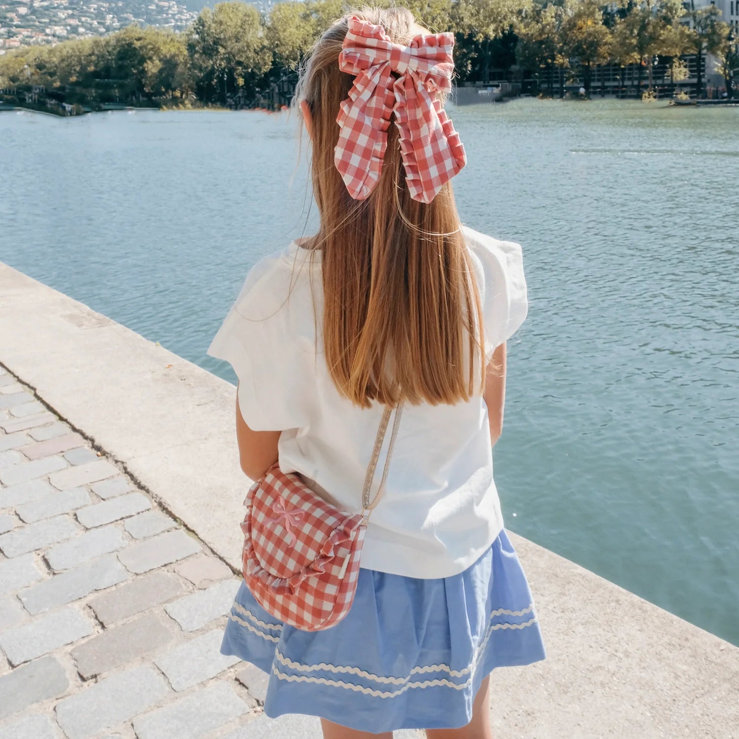 Woman with a large red and white checkered bow by a lake