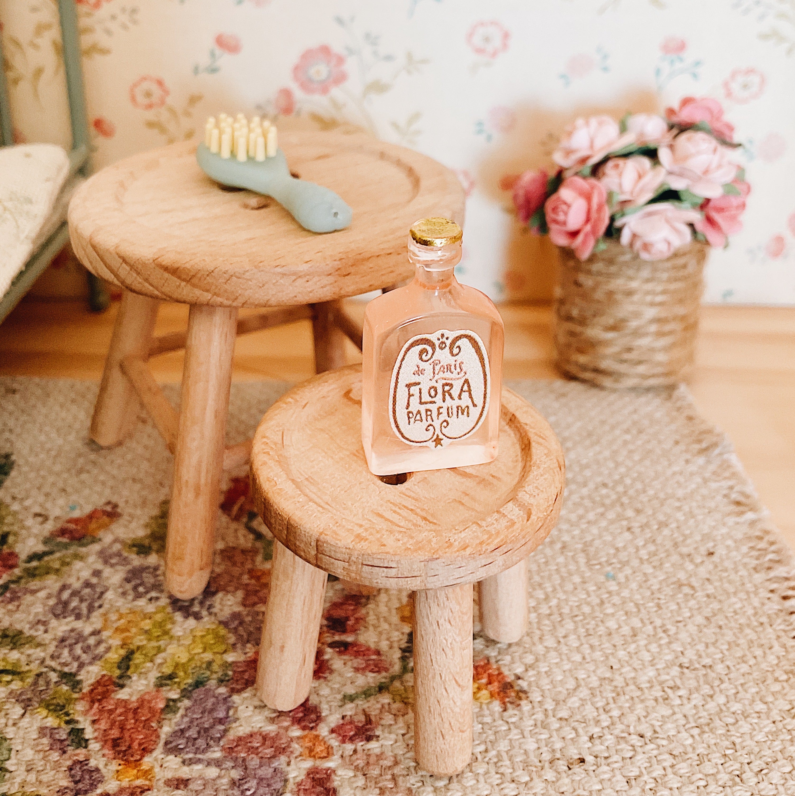 a maileg table and stool set arranged in a dolls house bedroom with some miniature accessories and a basket of flowers