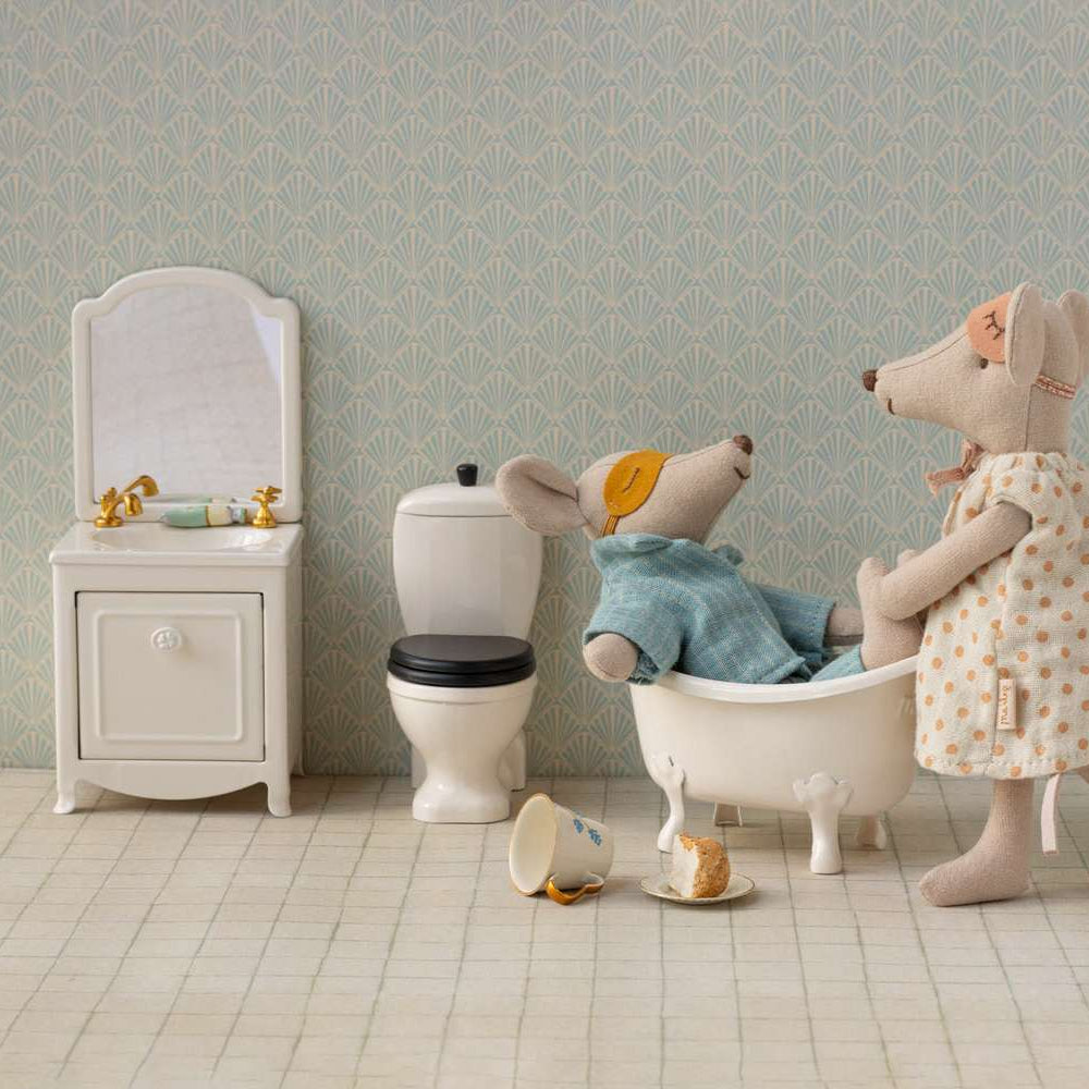 Stuffed animal toys in a bathroom setting with a bathtub and toilet.