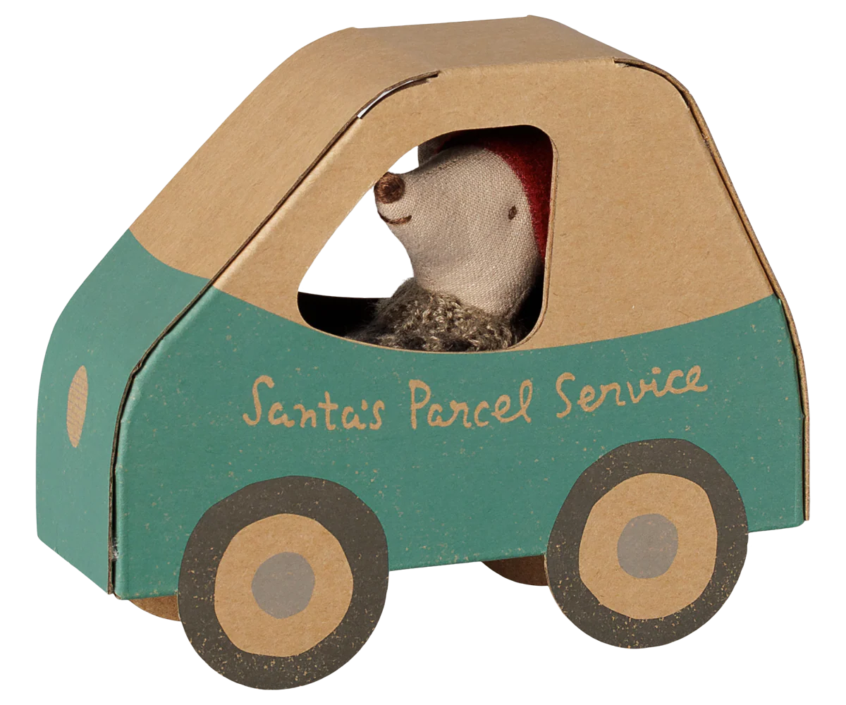 A small toy car shaped like a box, painted teal green on the lower half and natural kraft brown on the upper half, with the words 'Santa's Parcel Service' printed on the side. A stuffed hedgehog wearing a red Santa hat sits inside as the driver.