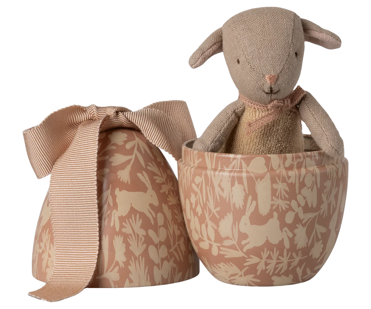 Stuffed animal toy in a patterned box with a matching bow on a white background
