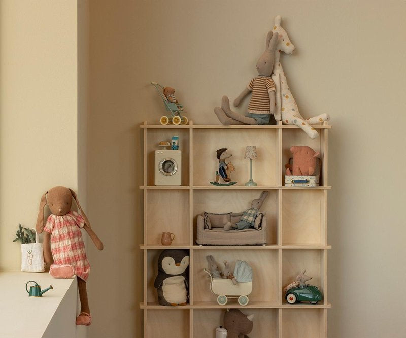 Wooden shelf with various toys and decorative items against a beige wall.